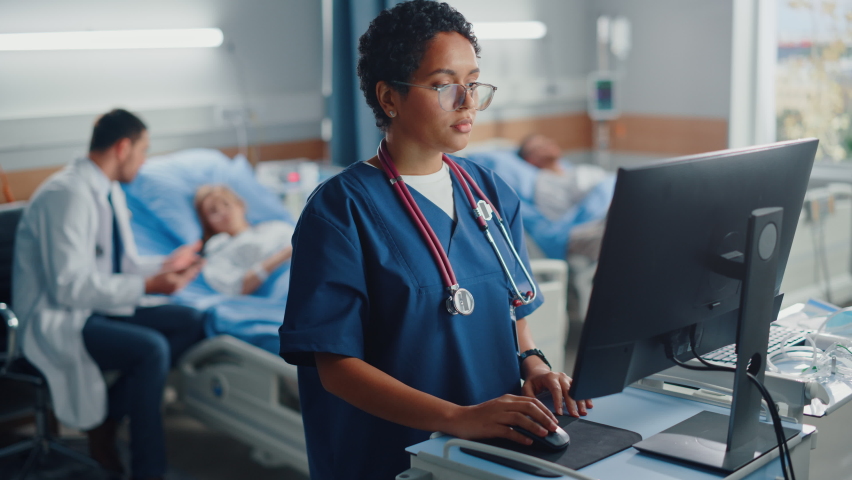 Hospital Ward: Professional Black Female Head Nurse Uses Medical Computer. In the Background Modern Equipment Clinic Doctor Consulting Patient Recovering After Successful Surgery in Bed Royalty-Free Stock Footage #1066174327