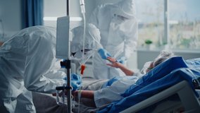 Hospital Coronavirus Emergency Department Ward: Team of Doctors wearing Coveralls, Face Shields Take Care of a Senior Patient Lying in Bed, Put Oxygen Mask and Lung Ventilator. Medics Saving Lives - Powered by Shutterstock - Get 15% off with code: PIKWIZARD15