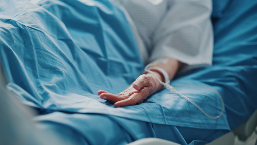 Hospital Ward: Senior Woman Resting and Recovering in Bed, Caring Daughter Holds Her Fragile Hand in Gesture of Support and Comforting. Focus on the Hands. Deeply Emotional Cinematic Shot Royalty-Free Stock Footage #1066174522
