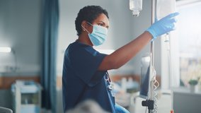 Hospital Ward: Professional Black Head Nurse Wearing Face Mask Does Checkup of Patient's Vitals, Checking Heart Rate Computer, Intravenous or Iv Fluids Drip Bag. Caring Nurse Monitors Person Recovery - Powered by Shutterstock - Get 15% off with code: PIKWIZARD15