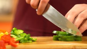 Close view man's hand chopping green fresh pepper with sharp knife. Chef is cutting green sweet paprika. Healthy Food Concept. Preparing Vegetable for salad. High quality 4k video.