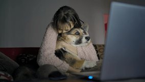 tender and kind young woman sits on couch with her welsh corgi dog and watching film together. girl hugs and strokes dog and shows something on laptop screen - Powered by Shutterstock - Get 15% off with code: PIKWIZARD15