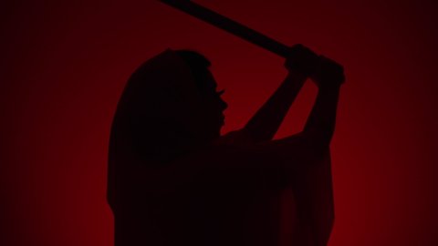 Brave shadow woman warrior with a japanese katana sword exercises in the martial art and waves her weapon. Reproduction reference of retro asian cinema. Slow motion