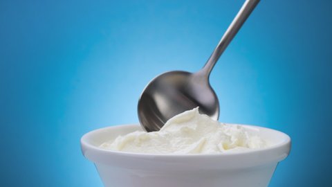 Whipped cream with spoon on blue background, greek yogurt
