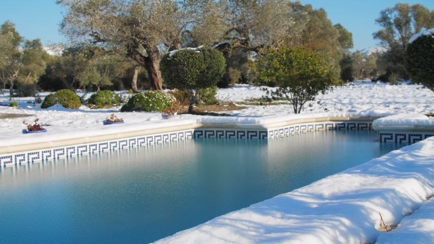 Beautiful and frozen swimming pool. Snowy landscape. Shadow of a person walking