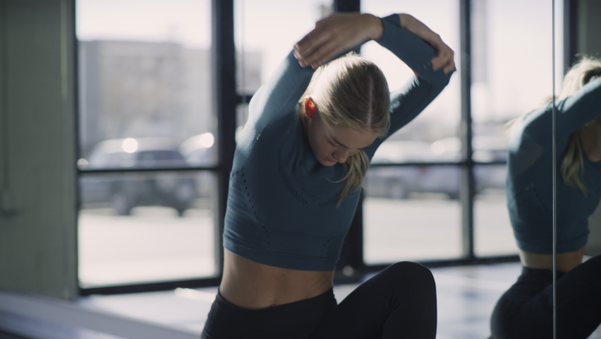 Woman in dance studio stretching neck and legs near mirror , Lehi, Utah, United States