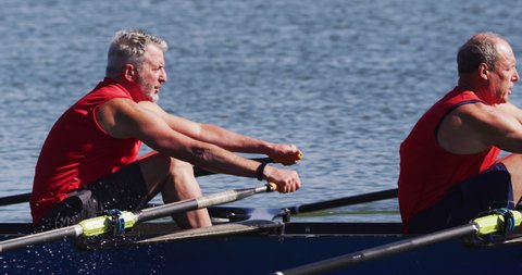 Two senior caucasian men rowing boat on a river. sport retirement leisure hobbies rowing healthy outdoor lifestyle.