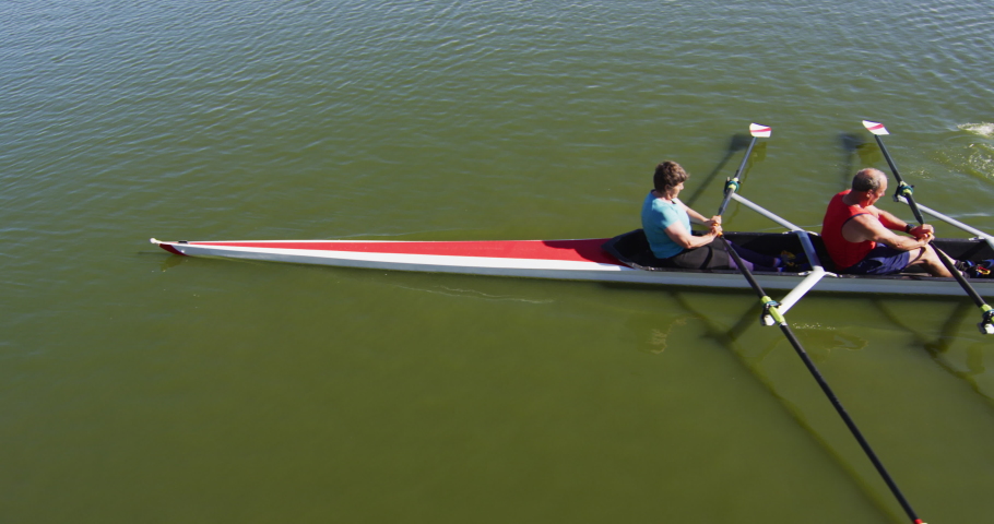 Senior caucasian man and woman rowing boat on a river. sport retirement leisure hobbies rowing healthy outdoor lifestyle.