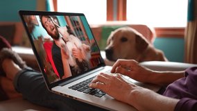 Closeup of laptop screen on woman lap with dog looking on of man talking with Husky dog. Remote video chat concept.