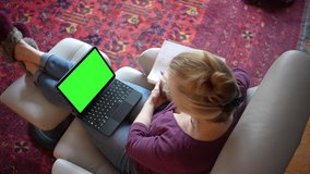 Overhead view of woman with notebook talking to green screen chroma key tablet computer with keyboard doing presentation to co-workers and friends.