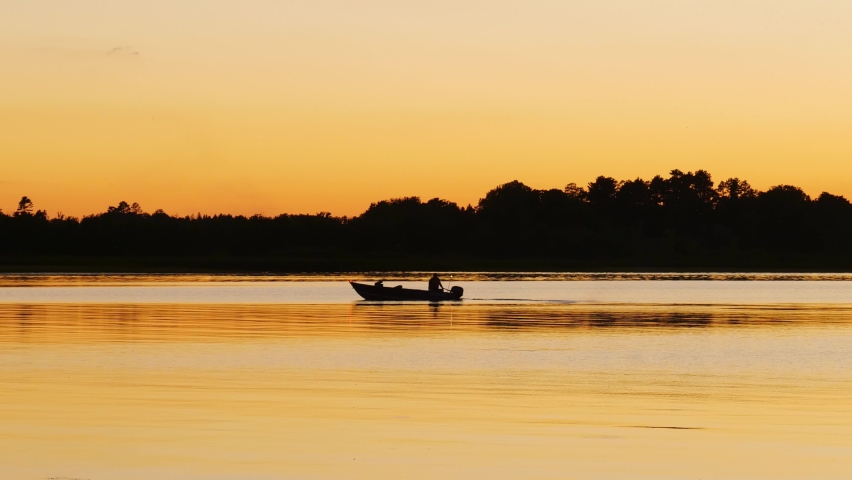Fishing boat on a beautiful lake in Minnesota on a serene and calm evening, in golden hour light. Royalty-Free Stock Footage #1066214344