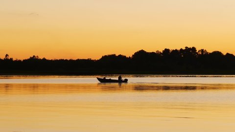 Fishing boat on a beautiful lake in Minnesota on a serene and calm evening, in golden hour light.