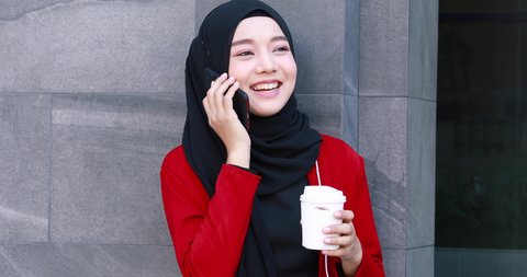 Portrait Young happy Asian muslim woman talking on mobile phone in city outdoor