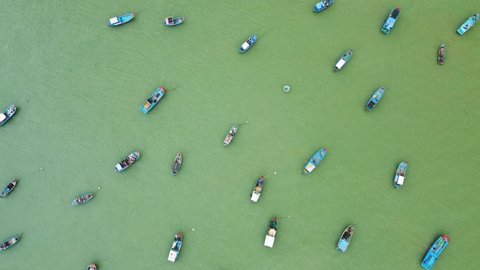 Awesome aerial view of anchored boats at Nha Trang Bay in Vietnam. Traditional Vietnamese fishing boats sways on waves. Scenic emerald water. Drone flying over sea.