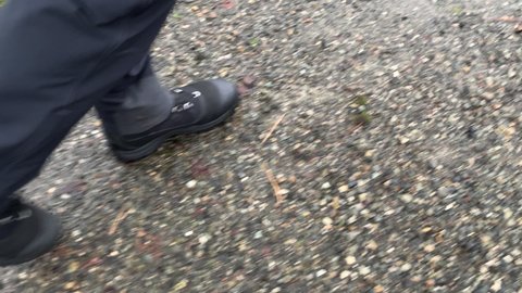 Slow motion close up of man's feet in boots walking on gravel on construction site 4k