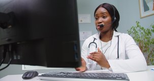 Close up of female doctor wearing headset making online video call consulting patient. Afro american woman therapist talking to camera in remote chat. Telemedicine, telehealth. Modern medecine concept