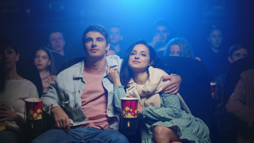 Romantic couple watching film in cinema. Happy man kissing girlfriend in dark hall. Cheerful woman looking to her boyfriend in movie theater. Royalty-Free Stock Footage #1066223578