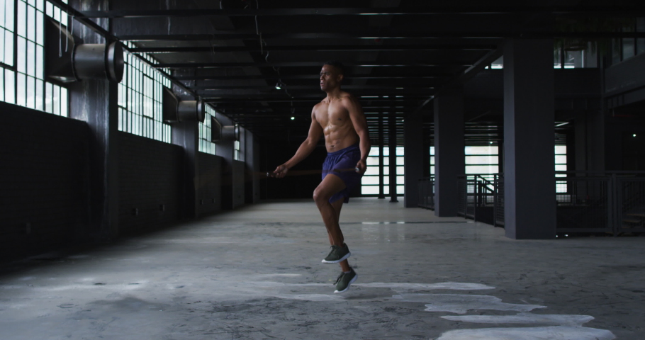 Shirtless african american man skipping the rope in an empty urban building. urban fitness and healthy lifetyle.