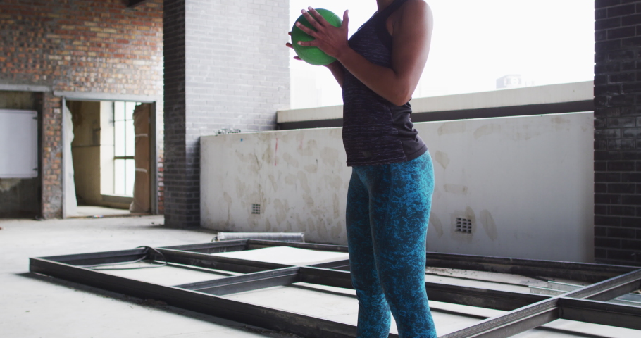African american woman exercising with medicine ball in an empty urban building. urban fitness and healthy lifetyle.