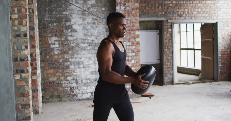 African american man exercising with medicine ball in an empty urban building. urban fitness and healthy lifetyle.