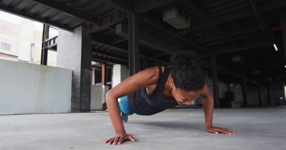 African american woman exercising doing push ups in an empty urban building. urban fitness and healthy lifetyle.
