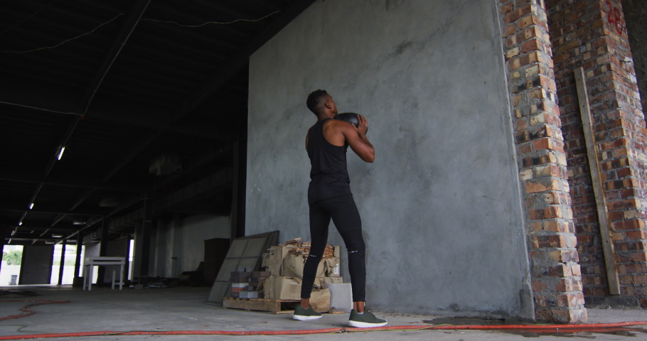 African american man exercising with medicine ball in an empty urban building. urban fitness and healthy lifetyle.