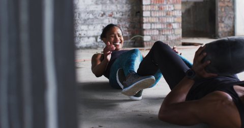 African american man and woman exercising with medicine ball in an empty urban building. urban fitness and healthy lifestyle.