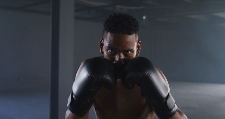 African american man wearing boxing gloves training throwing punches in empty room. urban sport, fitness and healthy lifestyle. Royalty-Free Stock Footage #1066234279