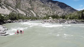 Aerial video filming of rafters on a catamaran, Altai Republic. Turquoise river Katun with turbulent flow, majestic mountains. The Ilgumensky rapids are a favorite place for rafters.