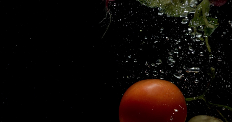 Super slow motion of falling broccoli, red tomatoes and potatoes into splashing water. Filmed on high speed cinema camera. Fresh natural vegetables in black background. | Shutterstock HD Video #1066237531