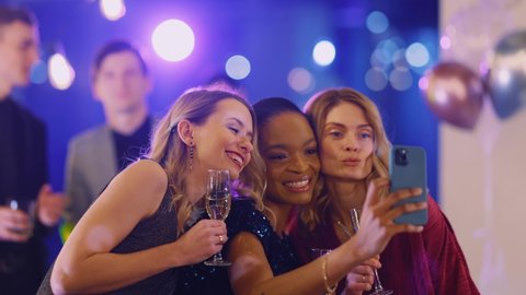 Beautiful trio of amazing attractive women taking selfie on mobile phone camera celebrating corporate night party event at the company.