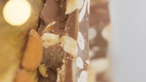 Close up of Turron, typical Christmas sweet in Spain. Almond nougat with chocolate on wood background spinning. Vertical video