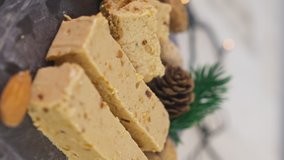 Close up of Turron, typical Christmas sweet in Spain. Almond nougat on black stone background spinning. Vertical video