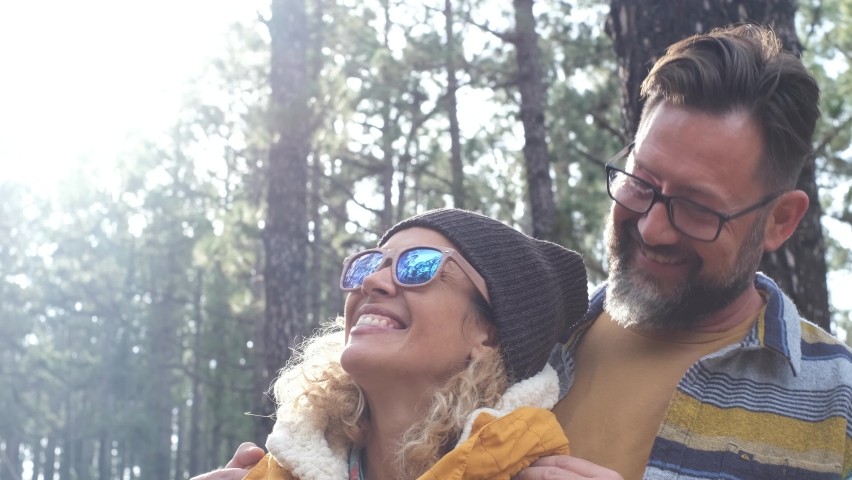 portrait of couple of two happy people looking at the trees in the forest and enjoying together the nature outdoors
