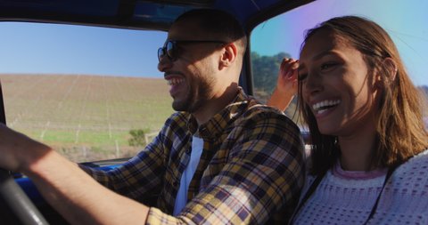 Side view close up of a young mixed race couple sitting in their pick-up truck, smiling and embracing during a road trip