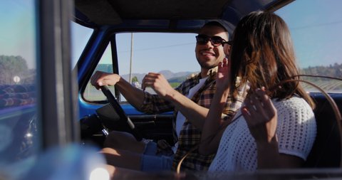 Side view of a young mixed race couple sitting in their pick-up truck, smiling and talking during a road trip