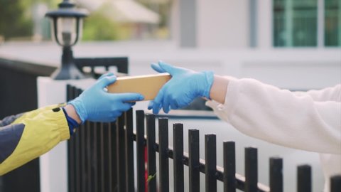 Close-up, male transport staff wearing gloves to deliver parcel boxes in front of the house to prevent covid-19 slow motion