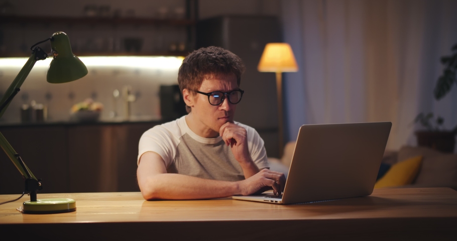 Tired freelancer guy rubbing eyes at workplace in home office tired of work with laptop. Exhausted man working on computer at table in evening and feeling stressed | Shutterstock HD Video #1066261978