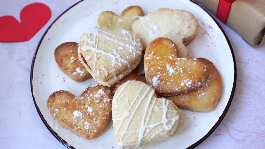 female hand takes heart shaped cookie from plate, valentine