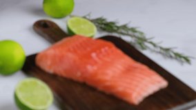 Salmon fish fillet on wooden cutting board with lime and rosemary. Shift focus. Concept of healthy seafood. 4K video