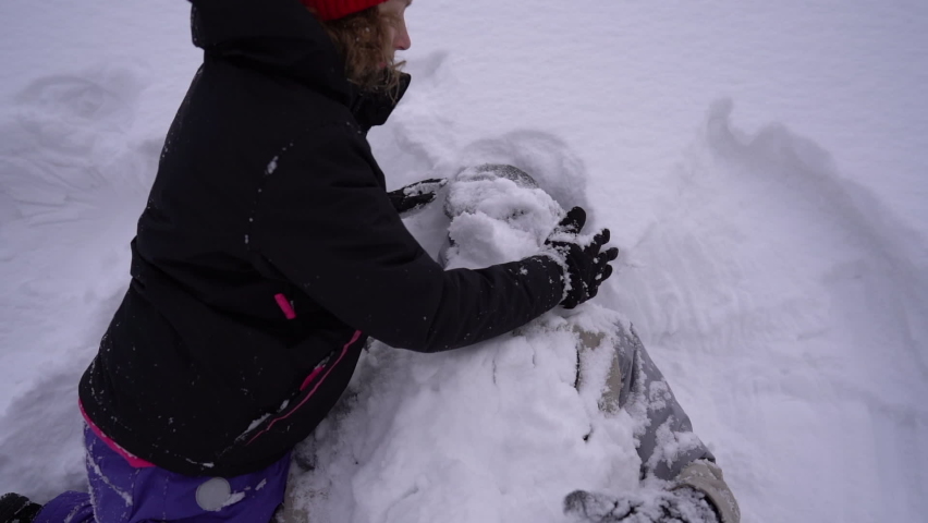 Snowball fight. Winter couple girl and boy are playing in the snow. The boy is completely buried in the snow. Snow on the face, funny video