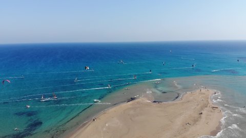 Scenic drone footage of kiteboarding and windsurfing in Prasonisi peninsula in Rhodes in Greece. Kitesurfing and windsurfing on the waves of Aegean Sea and calm flat water of Mediterranean Sea.