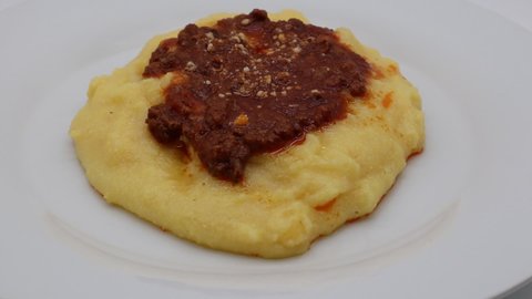 Polenta with bolognese sauce and parmesan cheese isolated on white