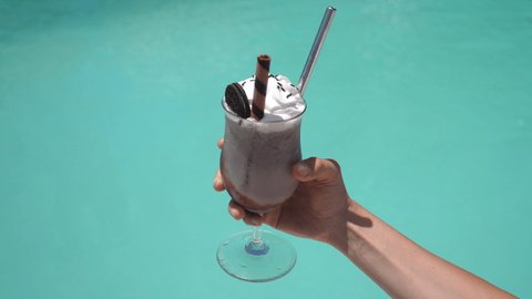 Close up of vegan chocolate milkshake with whipped cream decorated with Oreo cookies. Sustainable metal straw. 