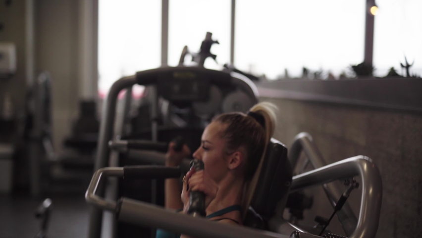 Woman at the gym doing arms exercises on a machine.