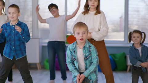 active childhood, boy with down syndrome dancing with a group of healthy children during a dance lesson closeup