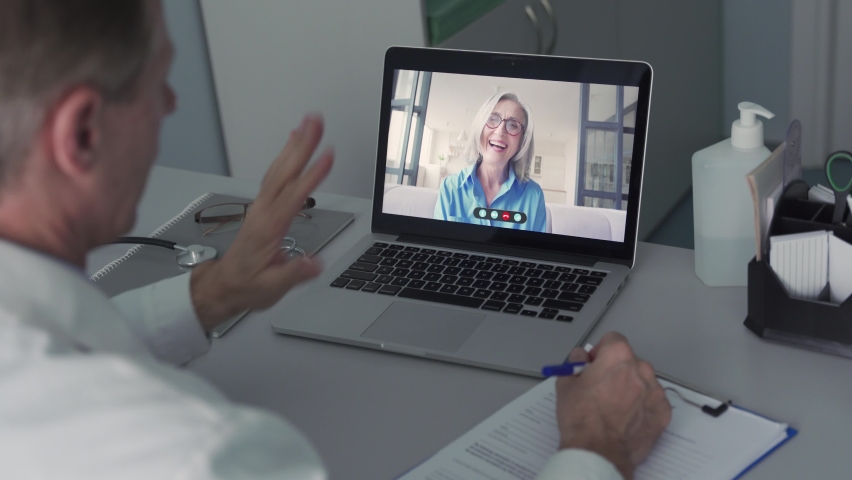 Older male doctor consulting senior old female patient by telemedicine online video call. Physician using telehealth medical chat virtual healthcare appointment on laptop computer. Over shoulder view Royalty-Free Stock Footage #1066285888