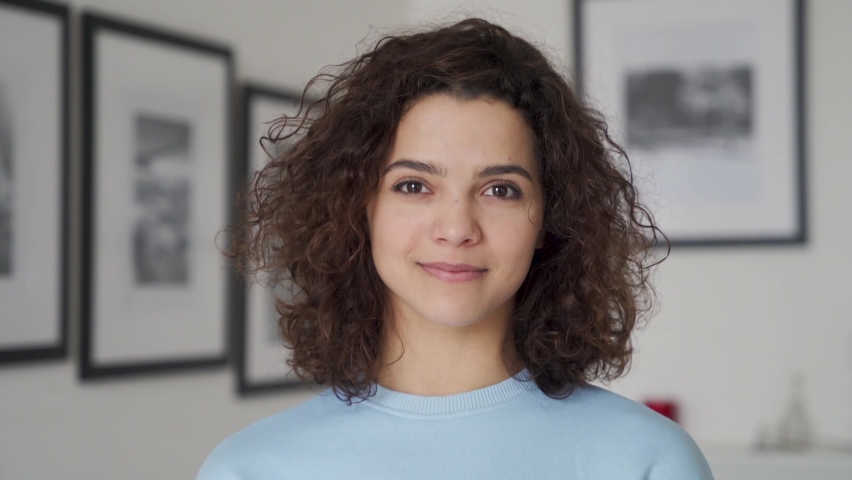Smiling cute young pretty hispanic latin woman looking at camera standing alone at home. Happy positive beautiful 20s girl female model posing indoors, close up view face headshot portrait. Royalty-Free Stock Footage #1066285924