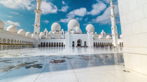 Entrance with queue of visitors to Sheikh Zayed Grand Mosque timelapse hyperlapse located in Abu Dhabi - capital city of United Arab Emirates. It is largest mosque in UAE. Blue cloudy sky