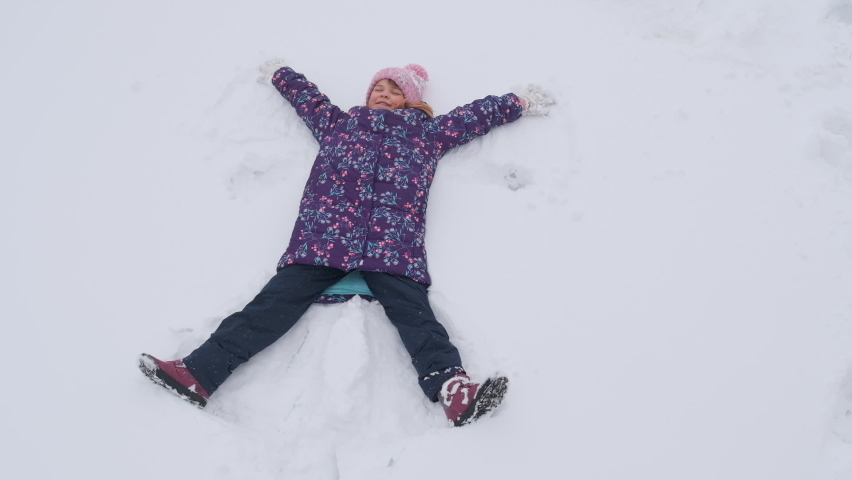 The girl lies in the snow. She makes a snow angel. | Shutterstock HD Video #1066299670